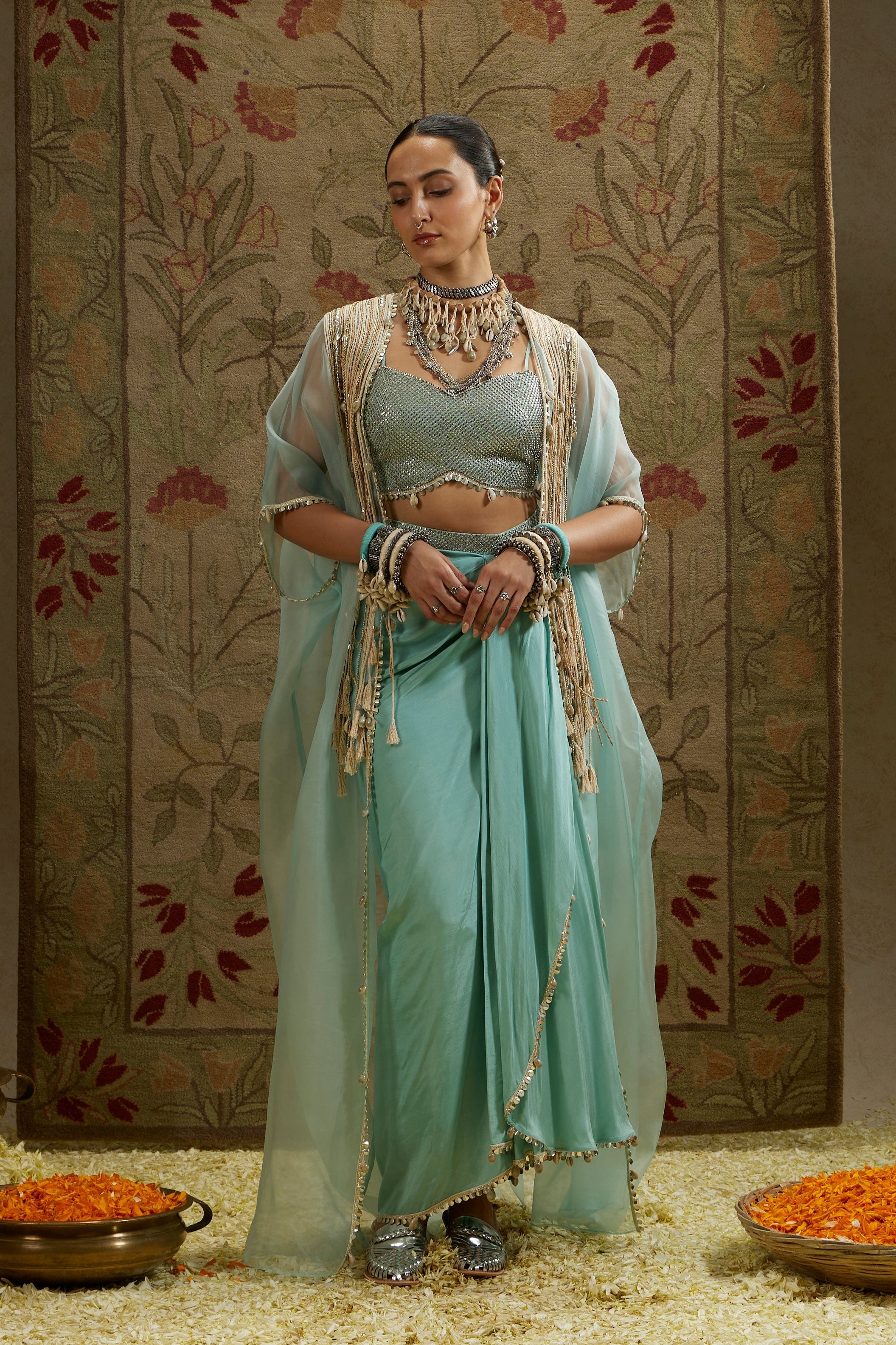 TEAL BLUE THREAD TASSLE CAPE PAIRED WITH METAL EMBELLISHED BUSTIER AND DRAPE SKIRT