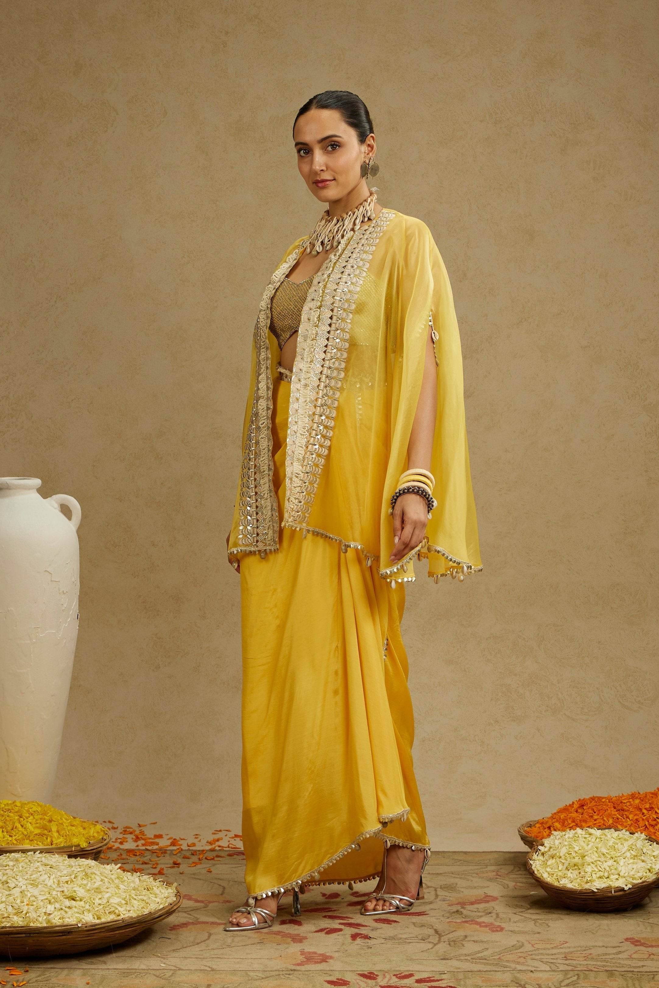 METAL EMBELLISHED BUSTIER PAIRED WITH ORGANZA CAPE AND YELLOW DRAPE SKIRT