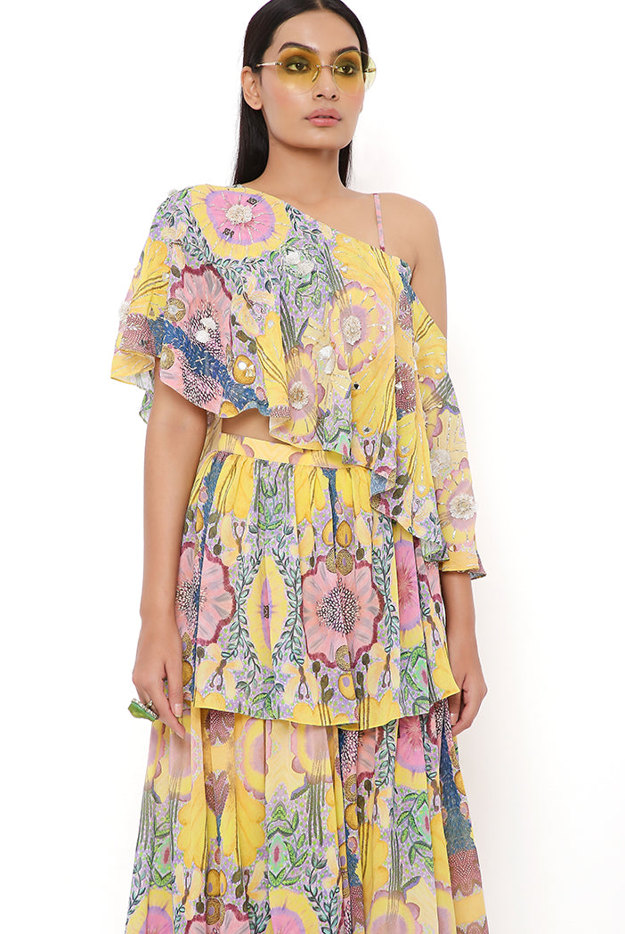 YELLOW ENCHANTED PRINT GEORGETTE EMBROIDERED ONE SHOULDER CAPE WITH BUSTIER AND FRILL SHARARA
